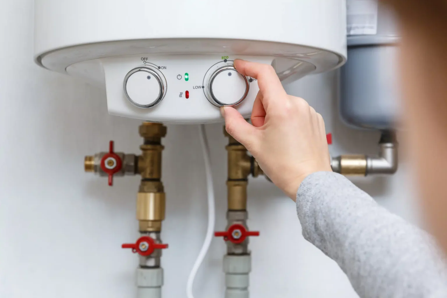 Homeowner adjusting the temperature controls on a water heater in San Diego